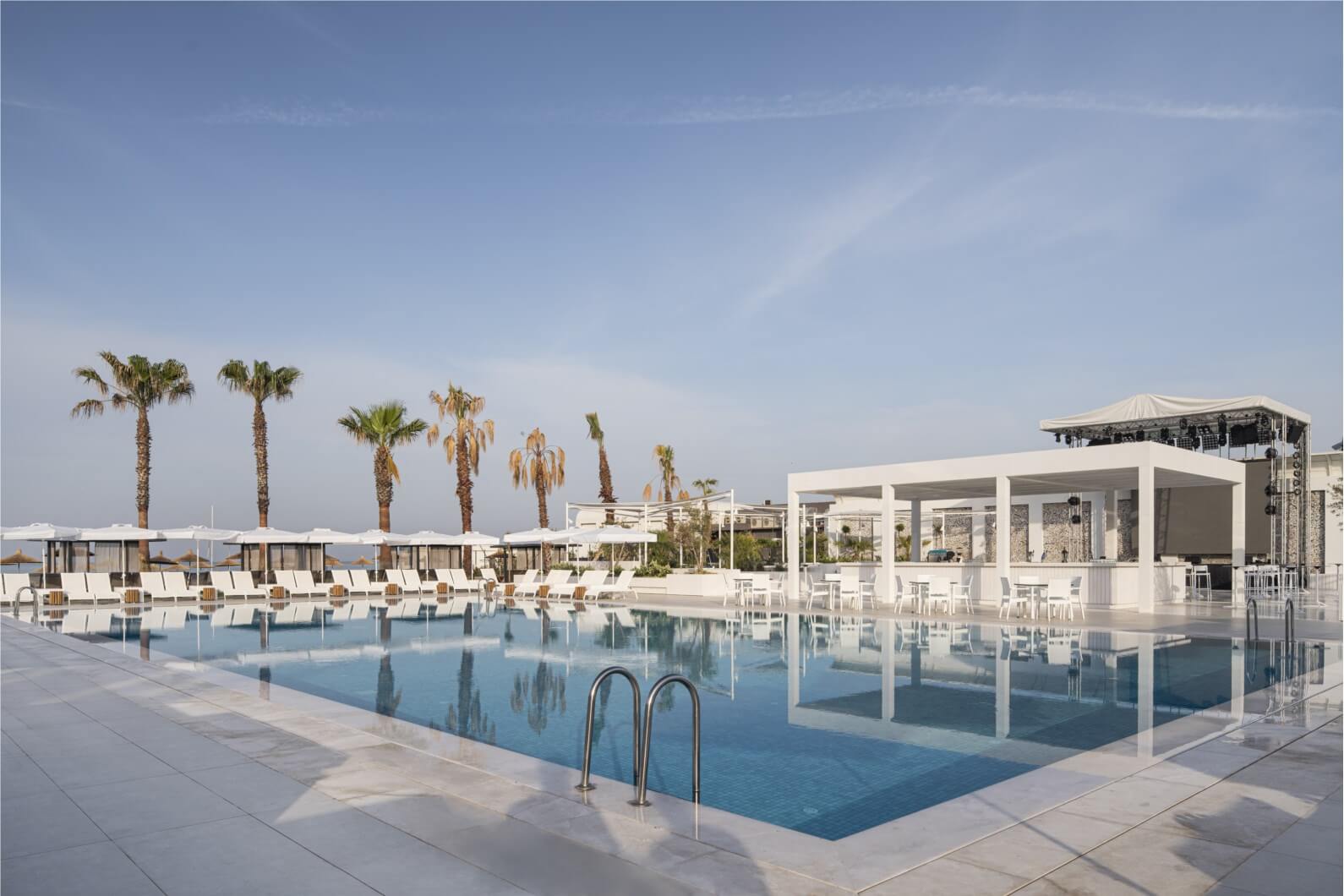 Outdoor swimming pool surrounded by sun loungers and a pool side bar at Voyage Belek Golf And Spa Hotel