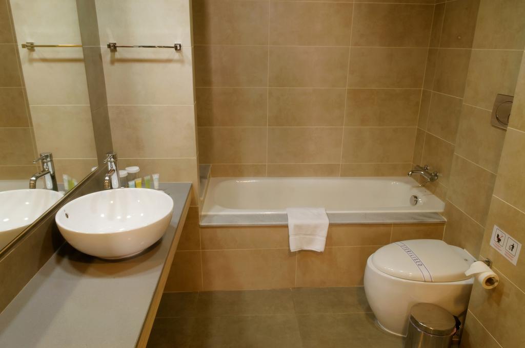 Bathroom Capital Coast Resort And Spa with bath tub, sink, mirror and toilet