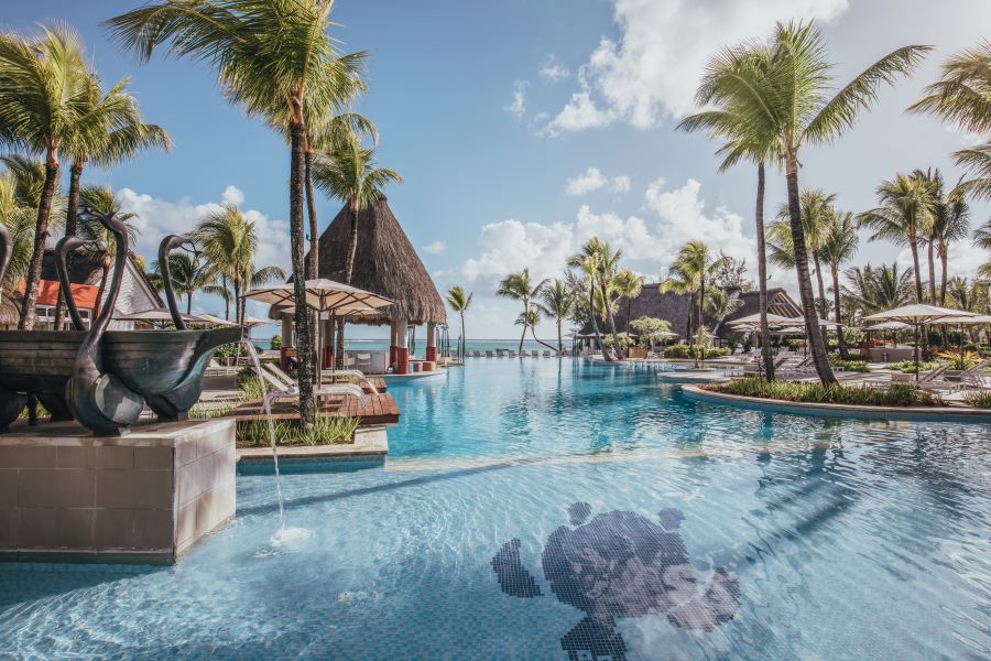 Swimming pool with palm trees leading to beach at Ambre Mauritius