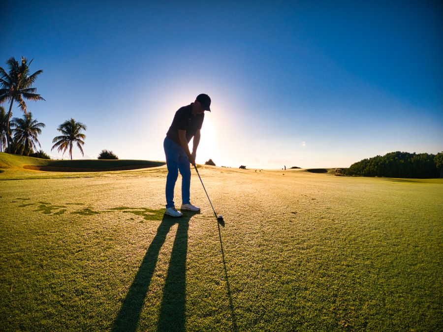 Golfer about to take shot with sun behind and blue sky at Anahita Golf in Mauritius