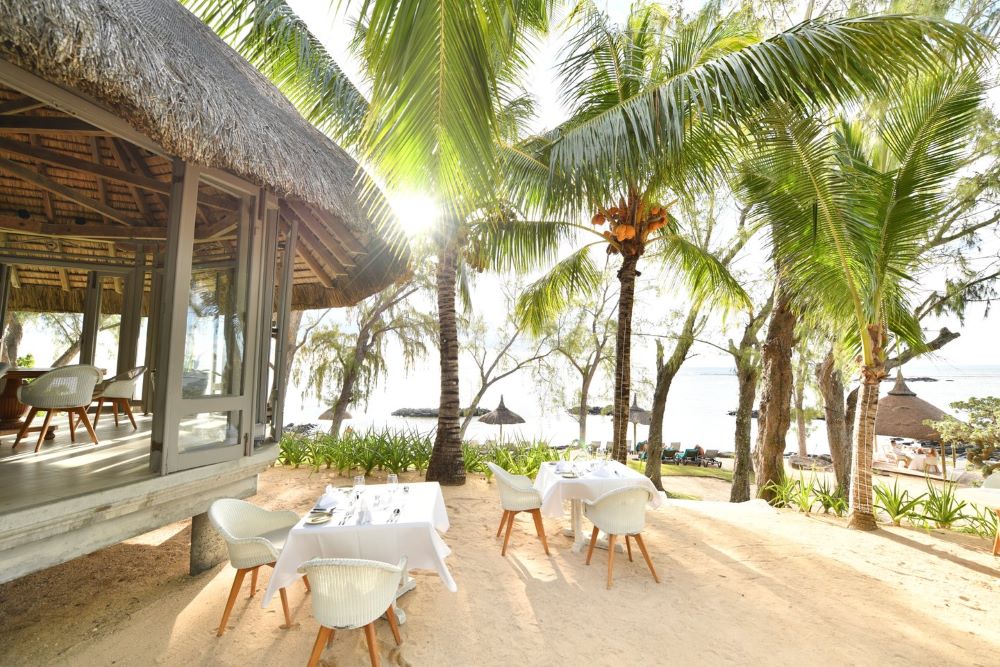 White table and chairs on decking at Canonnier Beachcomber Golf Resort & Spa