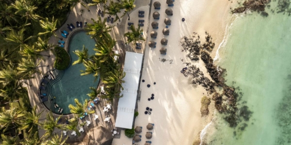 Beach and sun loungers in front of palm trees at Constance Belle Mare Plage Hotel Mauritius