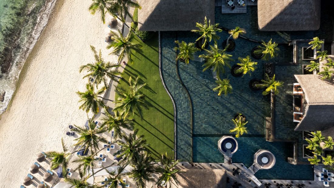 Resort meets white sand beach decorated with palm trees at Constance Belle Mare Plage Hotel Mauritius