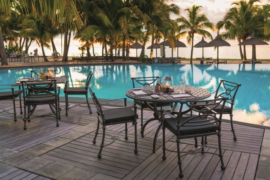 Swimming pool with tables and chairs beside at Dinarobin Beachcomber Golf Resort & Spa