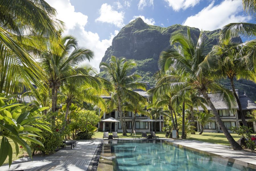 Swimming pool with mountain and palm trees behind at Dinarobin Beachcomber Golf Resort & Spa