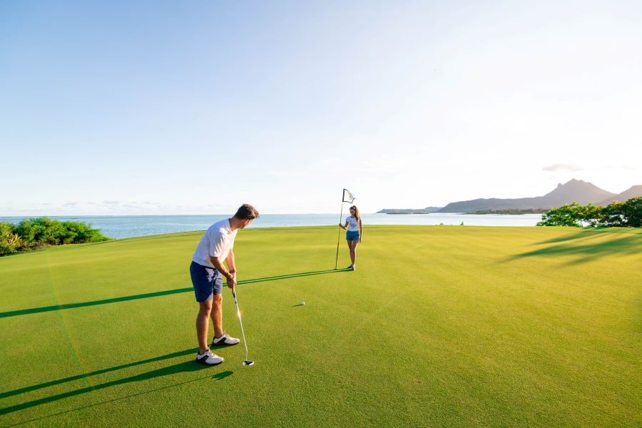 Two golfers on the putting green with Indian Ocean and putting green in the background