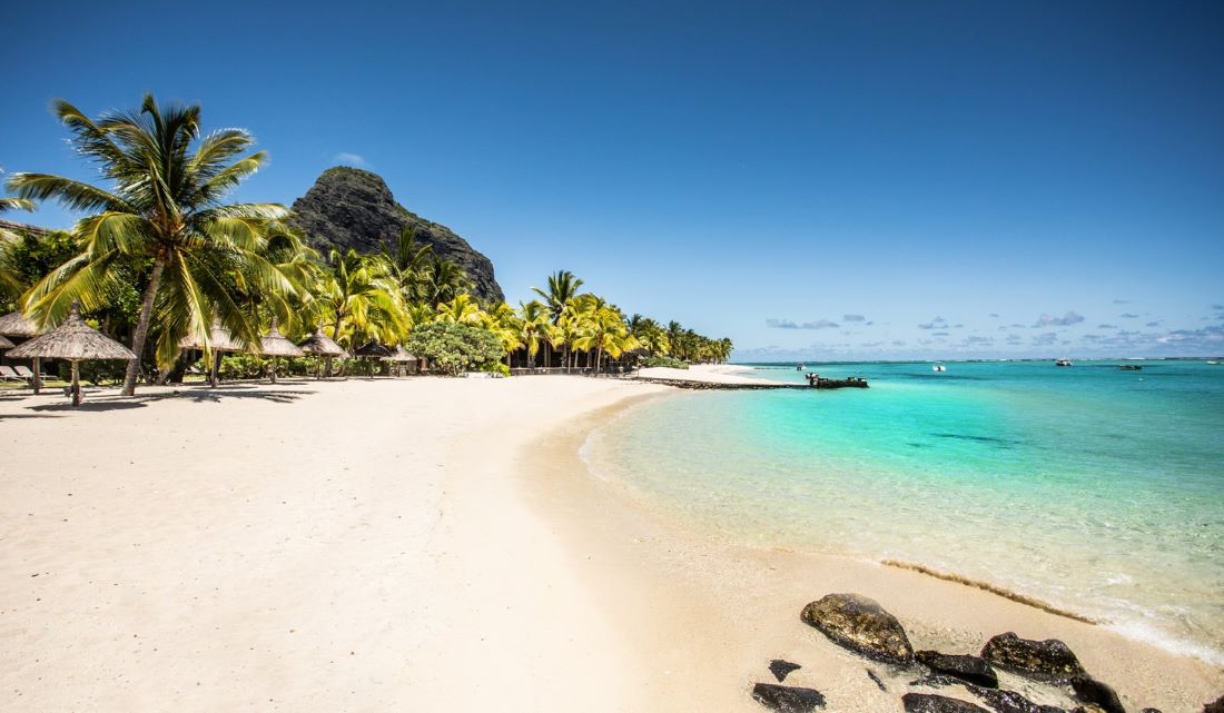 White sand beach with mountain in the distance at Paradis Beachcomber Golf Resort & Spa