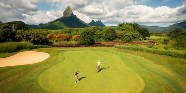 Two golfers on the green with mountain in the distance at Tamarina Golf Club