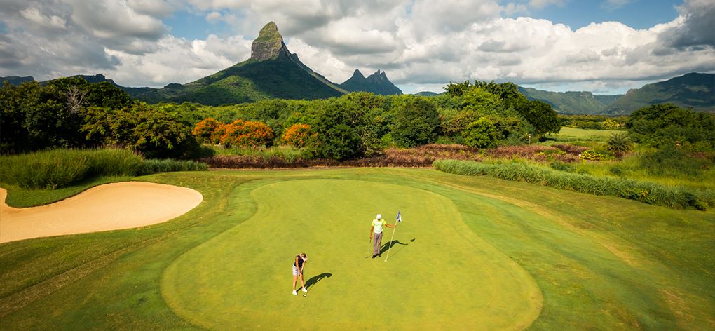 Two golfers on the green with mountain in the distance at Tamarina Golf Club