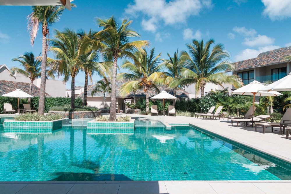 Swimming pool with palm trees and sun loungers at Anahita Golf And Spa Resort