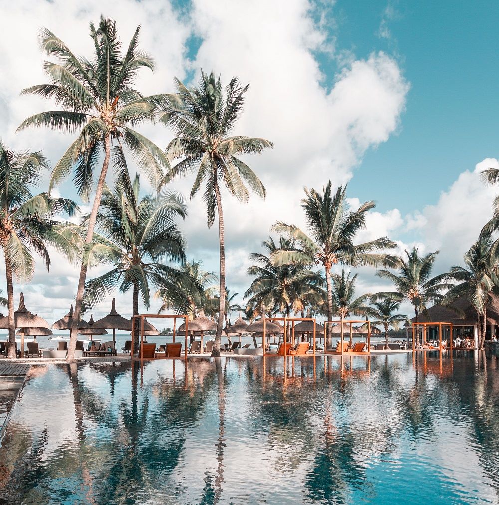 Palm trees overlooking the pool with white clouds and blue sky at Anahita Golf And Spa Resort