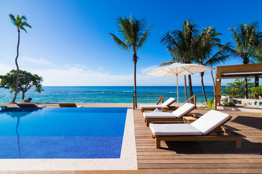 Sun loungers by swimming pool with palm trees at Casa de Campo Resort & Villas