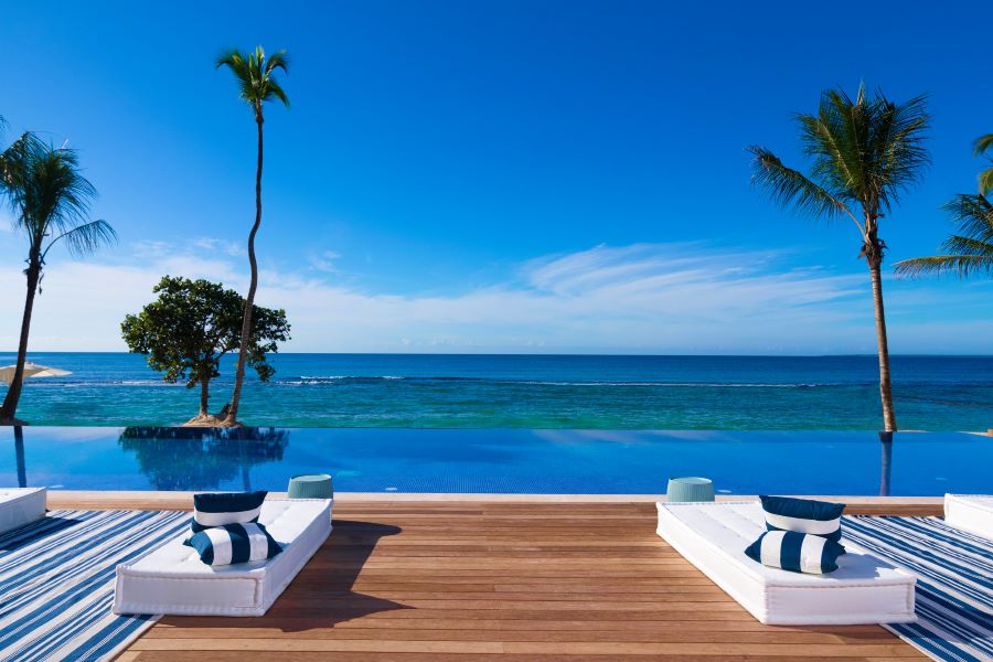 Sun loungers overlooking infinity pool and sea at Casa de Campo Resort & Villas