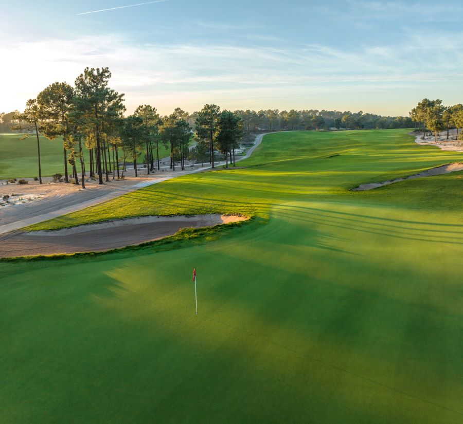 Lush green fairway and putting green with flag at Dunas Comporta Golf Course in Portugal