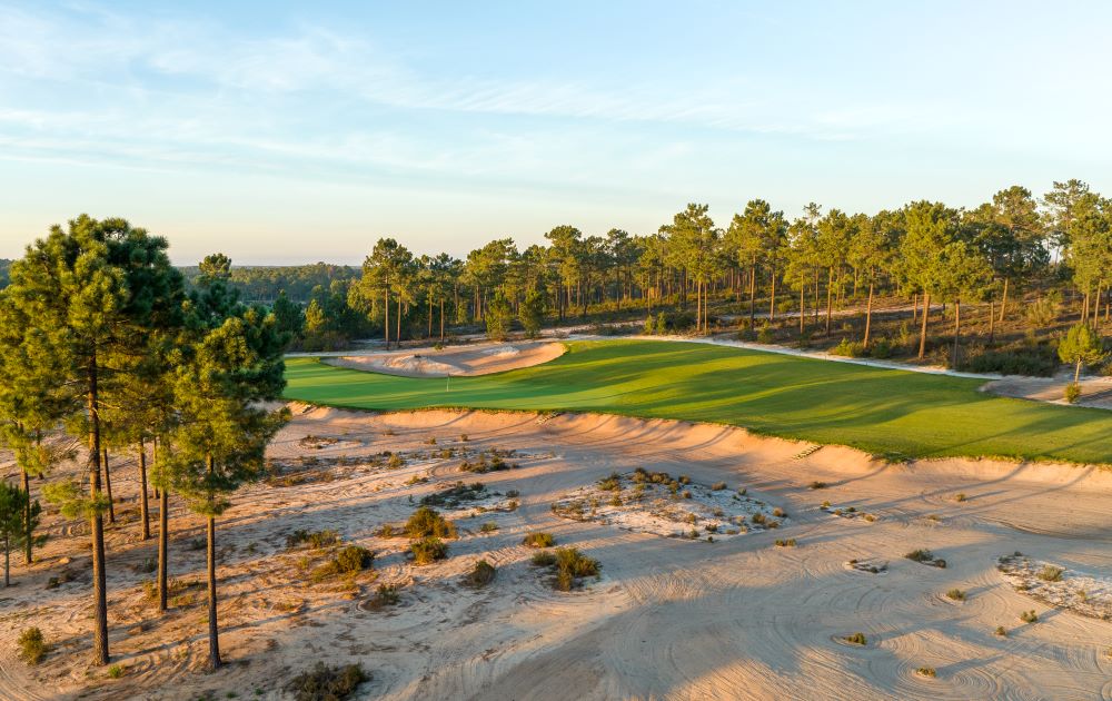 Sand dune protecting the course with trees in the distance at Dunas Comporta