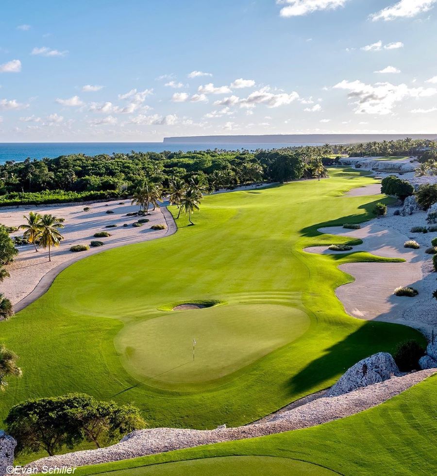 Lush green grass on the fairways, flanked by sand dunes