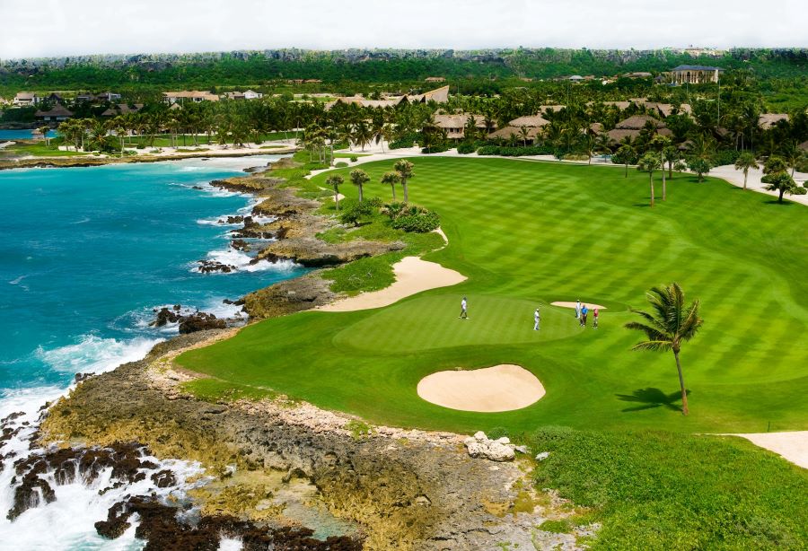 Sand bunkers protecting the green where golfers are currently putting to the hole at Punta Espada