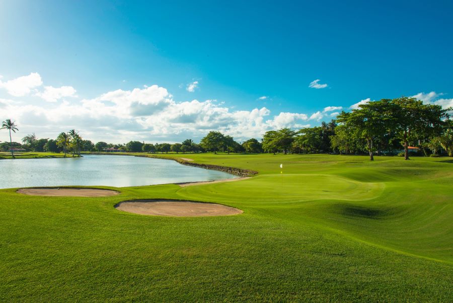 Lush green grass with lake to the left of the putting green at The Links Golf Course in Dominican Republic