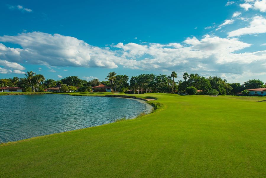 Blue lake to the left of lush green grass and blue sky overhead at The Links Golf Course