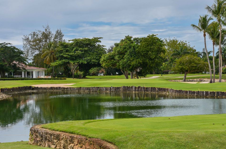 Lake bending in-between the fairway and the putting green with trees at the back at The Links Golf Course