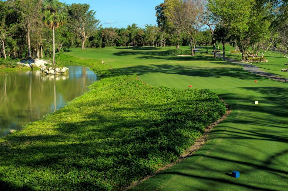 Green grass on fairway with blue sky overhead and river to the left at The Lakes Barcelo Course