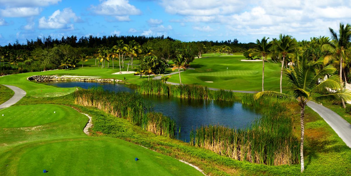 Blue lake and lush green grass of the golf course at The Lakes Barcelo Course