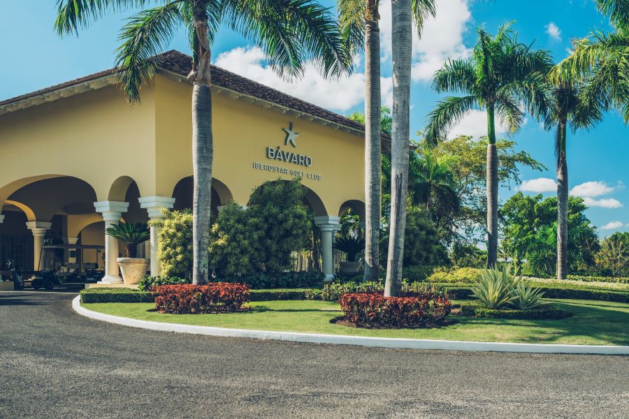 Yellow painted clubhouse at Iberostar Bavaro Golf Club with palm trees decorating the gardens