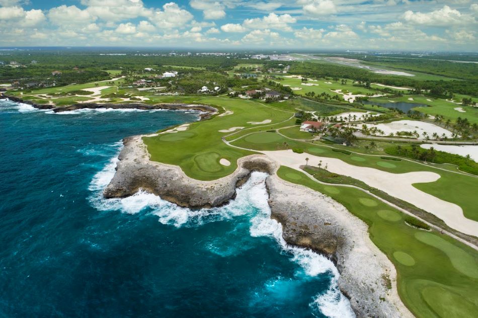 Blue sea water crashing against the rocks with the golf course nestled above at Corales Golf Club