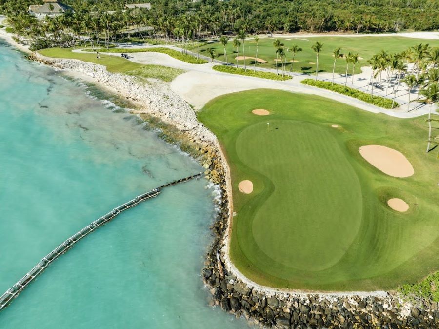 Putting green on the course at La Cana Golf protected by turquoise water