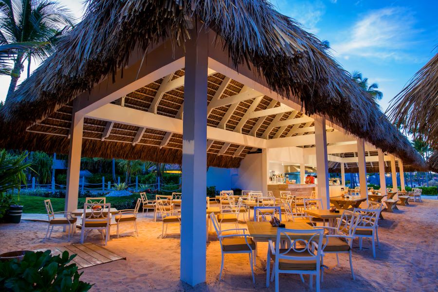 Wooden tables and chairs under thatched roof at Melia Caribe Beach Resort