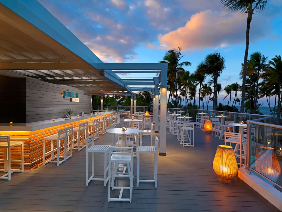 Bar with white stools and tables at Melia Punta Cana Beach Resort