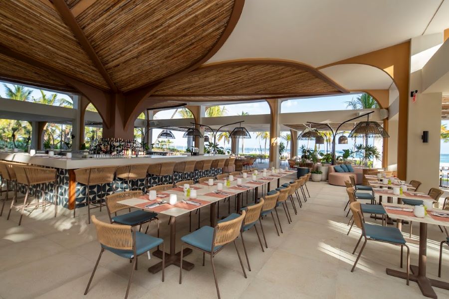 Large table in restaurant with bar in the distance, ready for service, at The Westin Puntacana Resort & Club in Dominican Republic