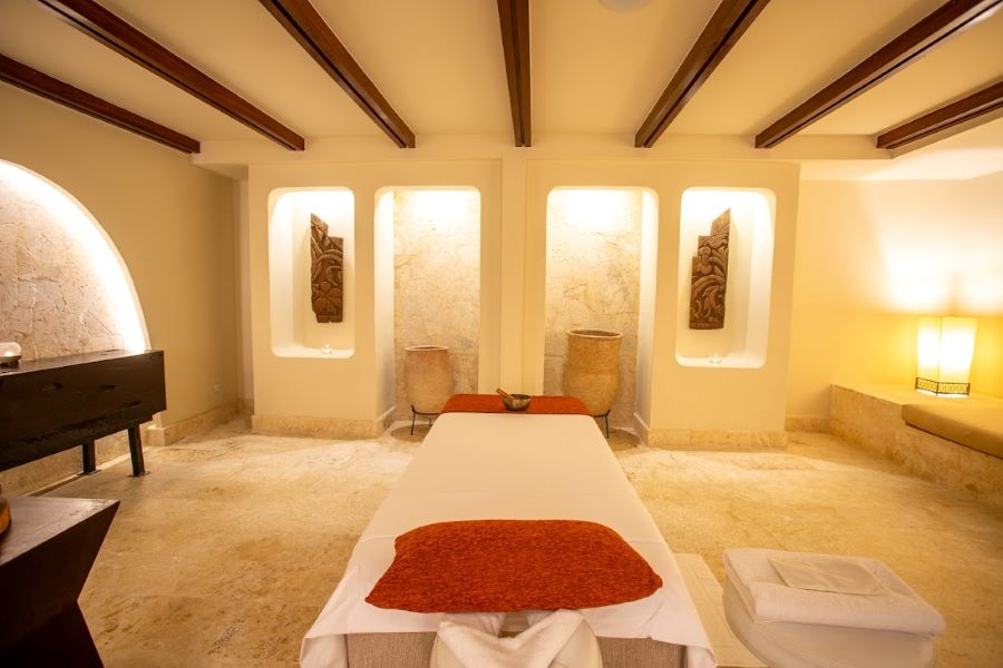 Spa treatment table with red pillow and white sheets and soft lighting at The Westin Puntacana Resort & Club