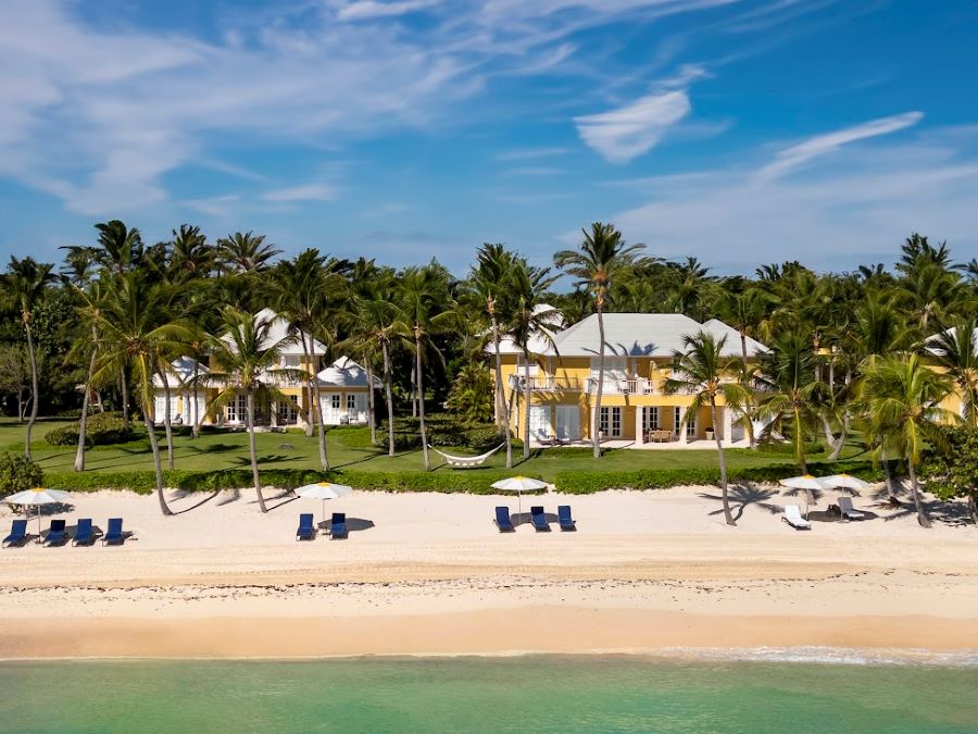 Villas with beach in front, with white sand and sun lougers and green palm trees at Tortuga Bay Hotel at Puntacana Resort & Club